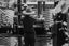 Two men working at a table outside with distillation equipment. Photo is black and white