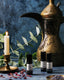 3 small glass roller bottles on a textured marble blue surface, surrounded by eucalyptus leaves and brass elements